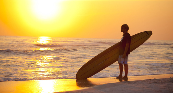 Surfer at sunset on South Walton Beach, courtesy Visit South Walton